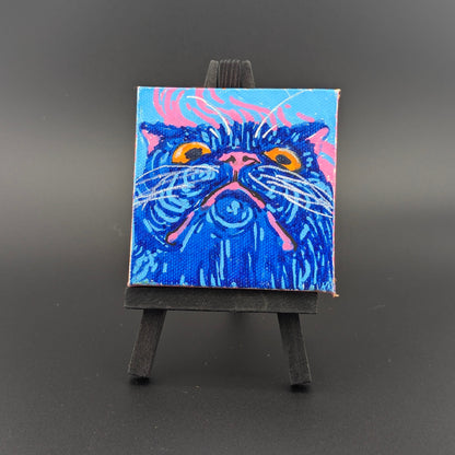 Small painting of a blue cat on a miniature easel