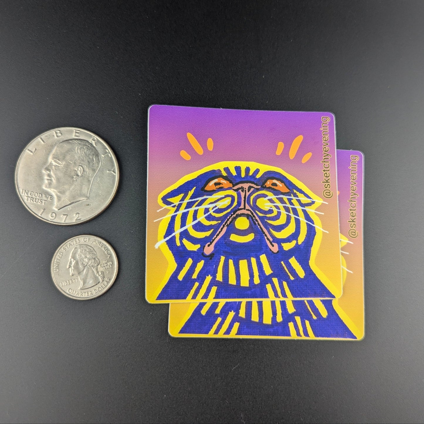 Sticker with a stylized face design next to two coins on a dark background