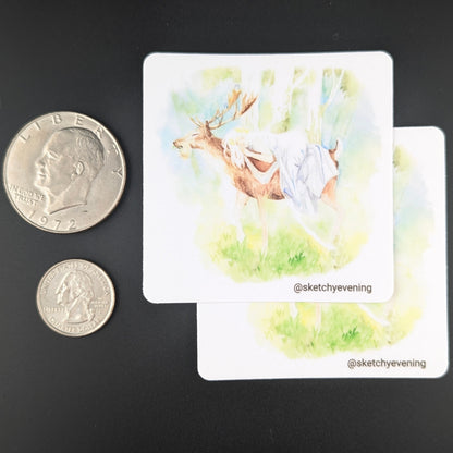 Small card with a nature-themed illustration on a dark surface, next to two coins for scale.