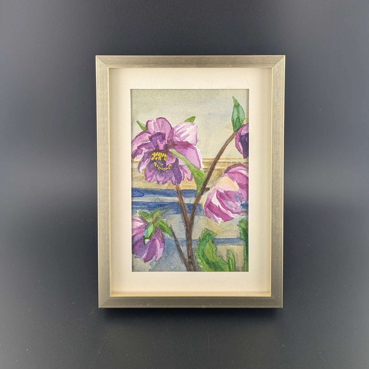 Framed artwork of purple flowers on a dark gray background